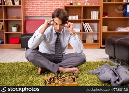 Young handsome boss playing chess during break 
