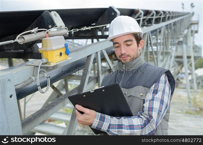 young handsome builder thinking about something and holding a clipboard