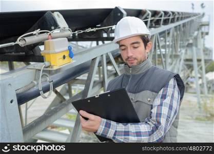young handsome builder thinking about something and holding a clipboard