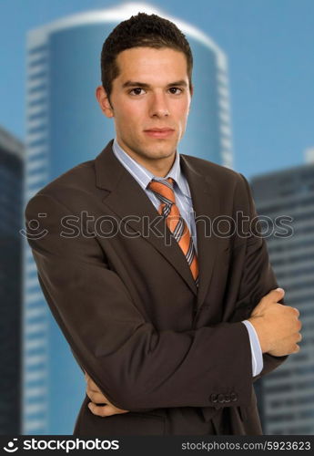 young handsome business man portrait with some office buildings behind