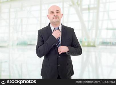Young handsome businessman adjusts his tie, at the office