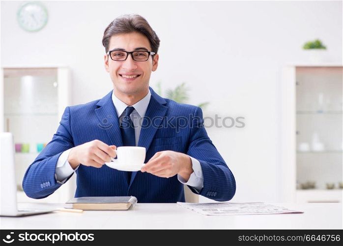 Young handsome businessman drinking coffee in the office 