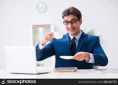 Young handsome businessman drinking coffee in the office 