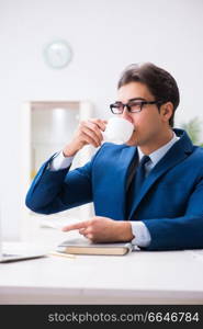 Young handsome businessman drinking coffee in the office . The young handsome businessman drinking coffee in the office 