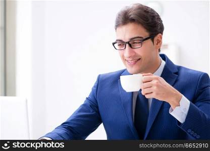 Young handsome businessman drinking coffee in the office 