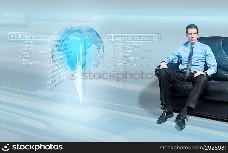 Young handsome businessman sitting on the sofa analyzing data from virtual holographic interface screen.