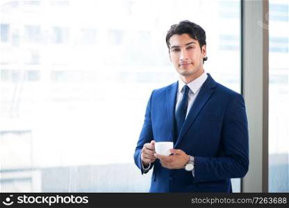Young handsome businessman standing at the window . The young handsome businessman standing at the window 
