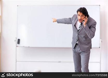 Young handsome businessman standing in front of whiteboard 