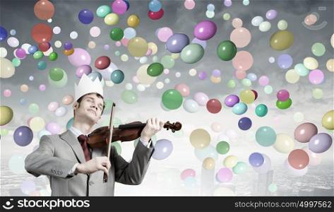 Young handsome businessman wearing white paper crown and playing violin. I&rsquo;m virtuos artist