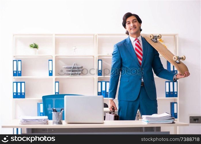 Young handsome businessman with longboard in the office 