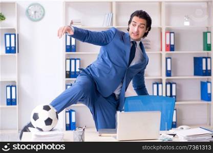 Young handsome businessman with soccer ball in the office 