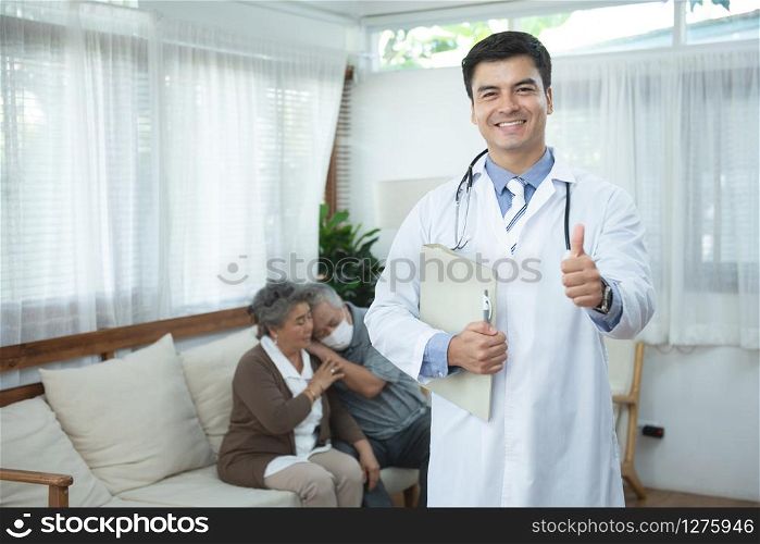 Young handsome caucasian male doctor standing hand holding document file look at camera with smile and two elderly old senior asian couple sit on couch in background,healthcare and medical concept.