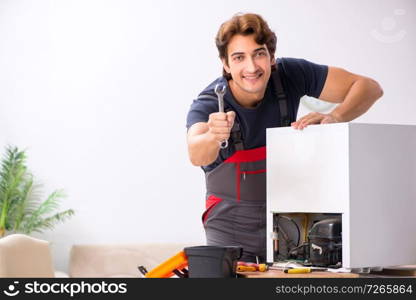 Young handsome contractor repairing fridge  . Young handsome contractor repairing fridge 