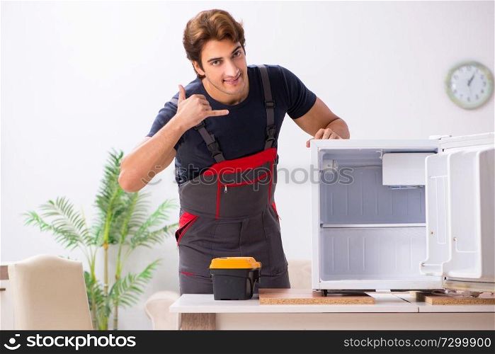 Young handsome contractor repairing fridge  . Young handsome contractor repairing fridge 