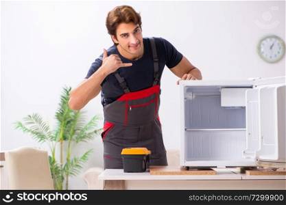 Young handsome contractor repairing fridge  . Young handsome contractor repairing fridge 