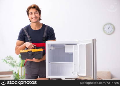 Young handsome contractor repairing fridge  . Young handsome contractor repairing fridge 