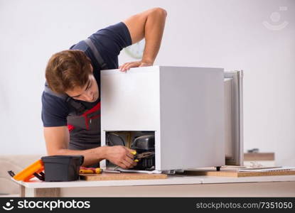 Young handsome contractor repairing fridge  . Young handsome contractor repairing fridge 