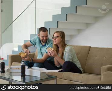 young handsome couple cheerfully spending time while eating pizza in their luxury home villa
