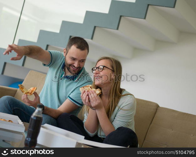 young handsome couple cheerfully spending time while eating pizza in their luxury home villa