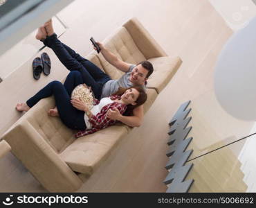 young handsome couple enjoying free time watching television with popcorn in their luxury home villa