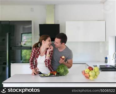 Young handsome couple in the kitchen beautiful woman preparing a salad while the man eating an apple