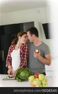 Young handsome couple in the kitchen beautiful woman preparing a salad while the man eating an apple