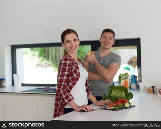 Young handsome couple in the kitchen beautiful woman preparing a salad while the man eating an apple