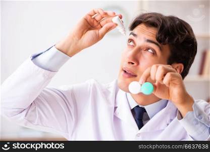 Young handsome doctor ophthalmologist with contact lenses in hospital . Young handsome doctor ophthalmologist with contact lenses in hos