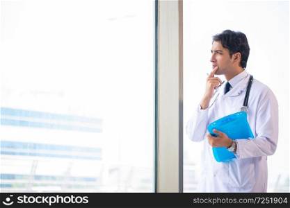 Young handsome doctor standing at the window 