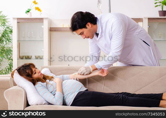 Young handsome doctor visiting pregnant woman at home 