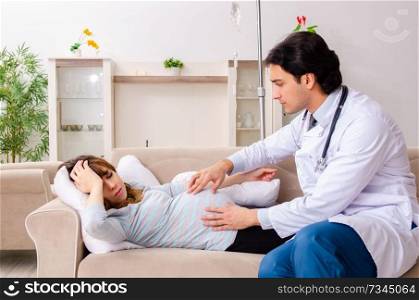 Young handsome doctor visiting pregnant woman at home 