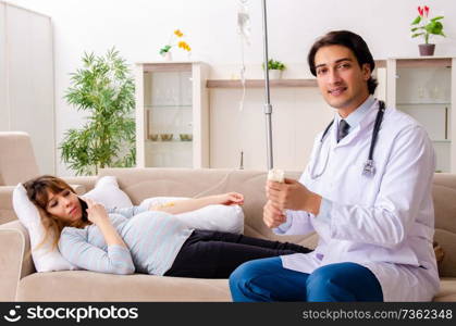 Young handsome doctor visiting pregnant woman at home