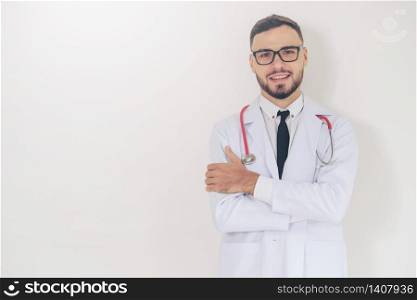 Young handsome doctor with arms crossed standing on white background. Medical and healthcare concept.. Young doctor with arms cross on white background.