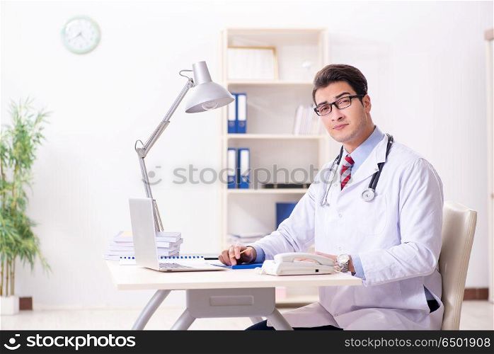 Young handsome doctor working in hospital room
