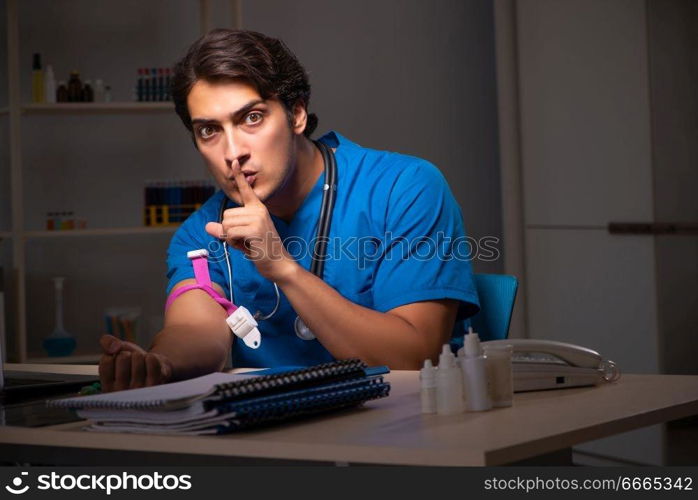 Young handsome doctor working night shift in hospital   