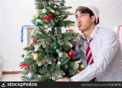 Young handsome employee celebrating Christmas at workplace 