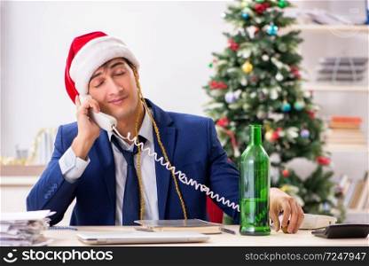 Young handsome employee celebrating Christmas at workplace
