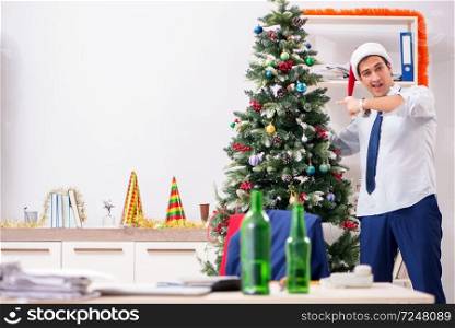 Young handsome employee celebrating Christmas at workplace 