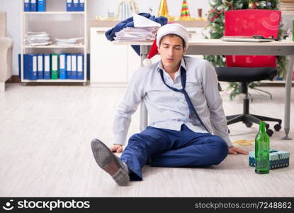 Young handsome employee celebrating Christmas at workplace 