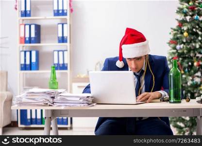 Young handsome employee celebrating Christmas at workplace . The young handsome employee celebrating christmas at workplace 