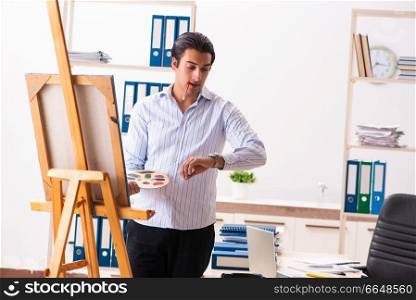 Young handsome employee enjoying painting at the office 