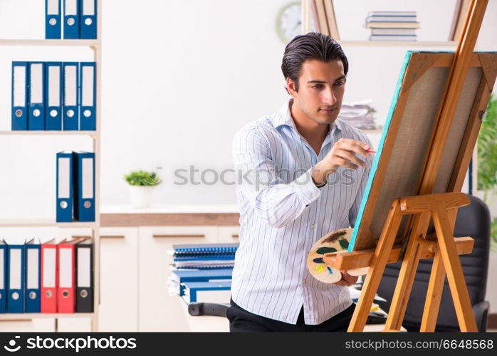 Young handsome employee enjoying painting at the office 