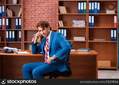 Young handsome employee sitting in the office  