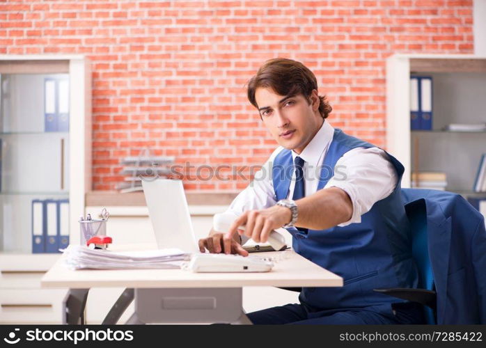 Young handsome employee working in the office 