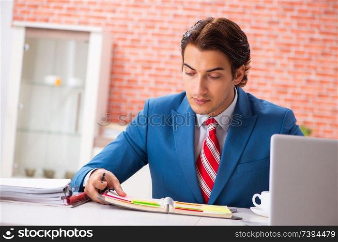 Young handsome employee working in the office 
