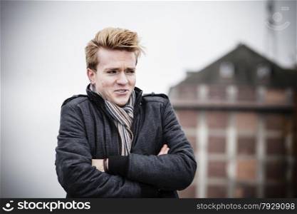 Young handsome freezing man fashion model casual style on street urban industrial background. Cold foggy day