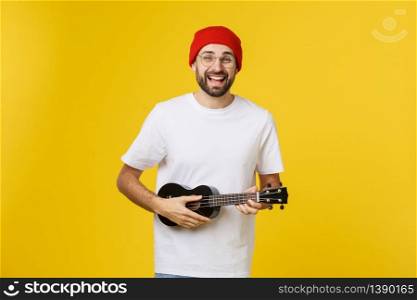 Young handsome guitar player. Studio shot on yellow background. Young handsome guitar player. Studio shot on yellow background.