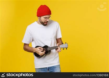 Young handsome guitar player. Studio shot on yellow background. Young handsome guitar player. Studio shot on yellow background.