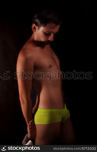 young handsome guy in green shorts and white hat on black background&#xA;