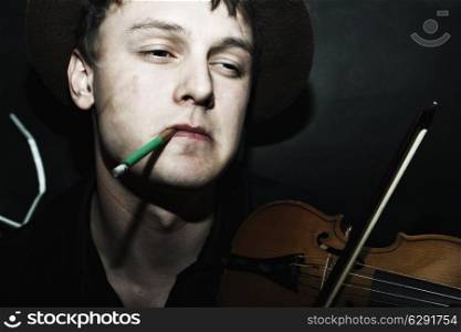 young handsome guy in hat with cigarette, playing the violin